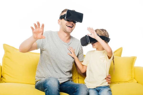 Father and daughter in virtual reality headsets on yellow sofa isolated on white — Stock Photo