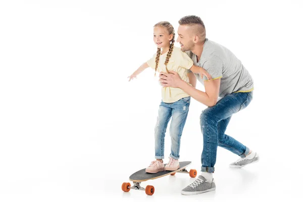 Padre ayudando a su hijita a patinar en monopatín aislado en blanco - foto de stock