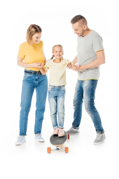 Smiling family holding hands of little daughter on skateboard isolated on white — Stock Photo
