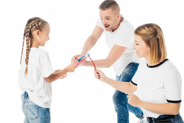 Família em roupas semelhantes brincando com escovas de dentes isoladas em branco — Fotografia de Stock