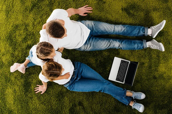 Overhead view of family with laptop resting on green lawn — Stock Photo