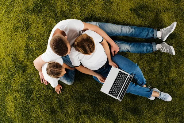 Vista aerea della famiglia con computer portatile appoggiato sul prato verde — Foto stock