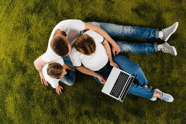 Vue aérienne de la famille avec ordinateur portable reposant sur la pelouse verte — Photo de stock