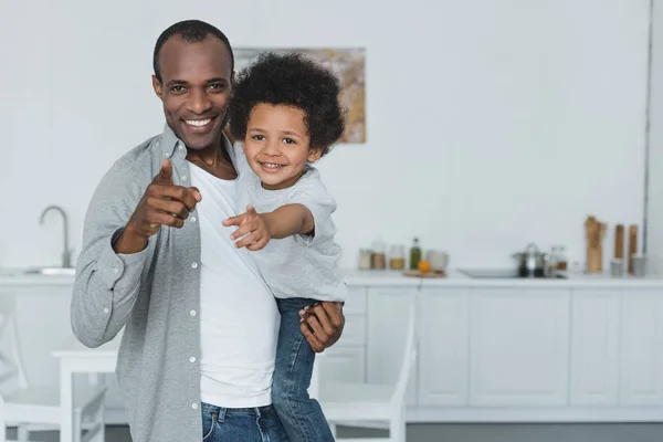 Afroamericano padre e hijo apuntando en cámara en casa - foto de stock