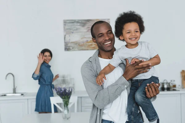 Афроамериканський батько обіймає сина і матір махає рукою вдома — стокове фото