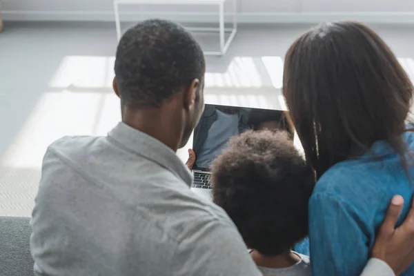 Vue arrière des parents afro-américains et fils utilisant un ordinateur portable dans le salon — Photo de stock