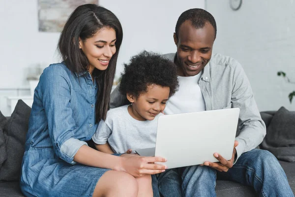African american parents and son holding laptop and sitting on sofa at home — Stock Photo