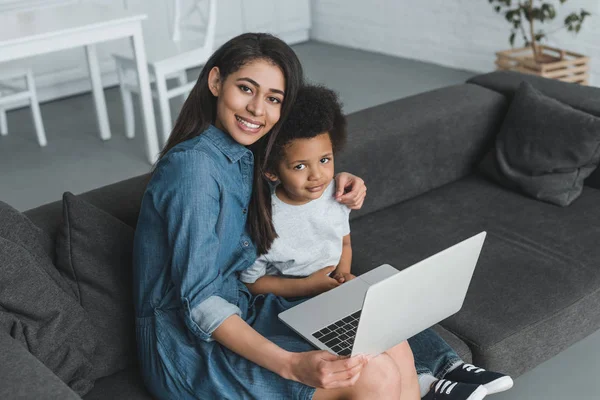 Aus der Vogelperspektive: Afrikanisch-amerikanische Mutter umarmt Sohn und hält Laptop zu Hause — Stockfoto