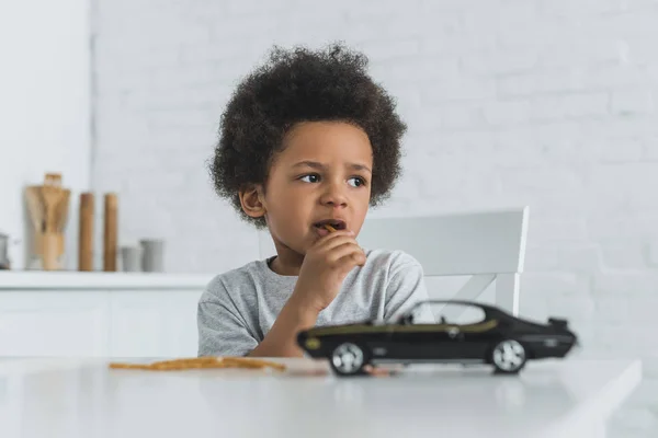 Adorable african american boy eating crispy breadsticks at home — Stock Photo