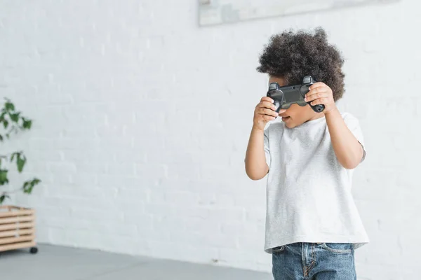 Adorable afroamericano chico celebración gamepad en casa - foto de stock