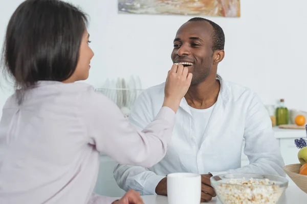 Afro-americano namorada alimentando namorado com pipocas em casa — Fotografia de Stock