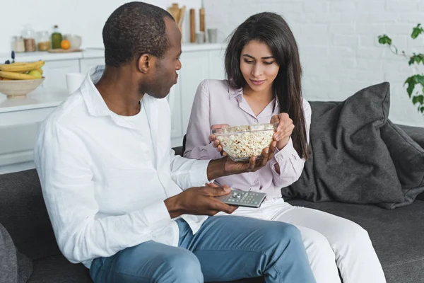 African american girlfriend and boyfriend eating popcorn and watching tv at home — Stock Photo