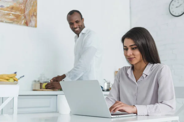 Africano americano fidanzata utilizzando computer portatile e fidanzato cucina a cucina — Foto stock