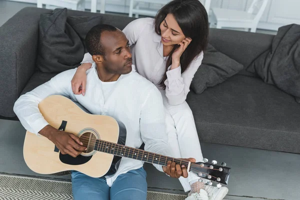 High angle view of african american boyfriend playing guitar for girlfriend at home — Stock Photo