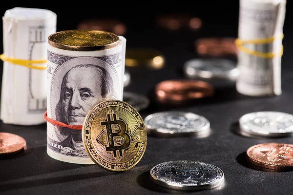 Close-up view of rolled dollar banknotes and bitcoins on black — Stock Photo