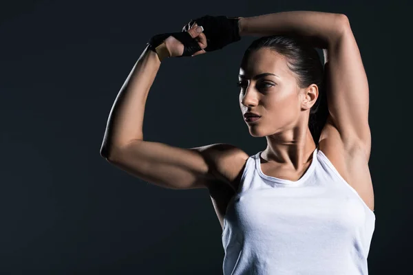 Strong sportswoman showing muscular biceps, isolated on grey — Stock Photo