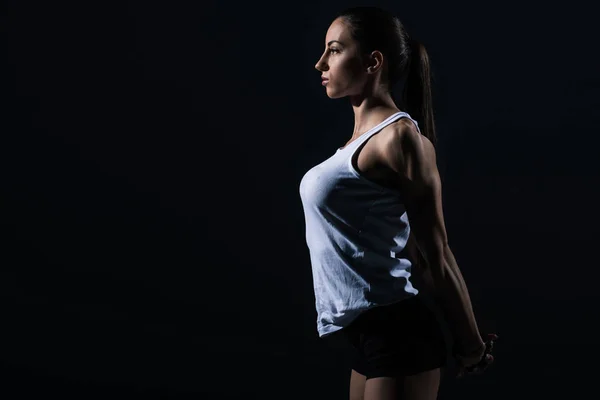 Beautiful athletic sportswoman stretching arms, isolated on black — Stock Photo