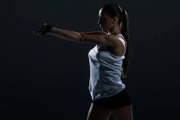 Attraktive, starke Bodybuilderin, die Arme ausstreckt, isoliert auf schwarz — Stockfoto