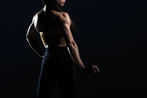 Bodybuilder féminin posant et montrant les muscles, isolé sur noir — Photo de stock