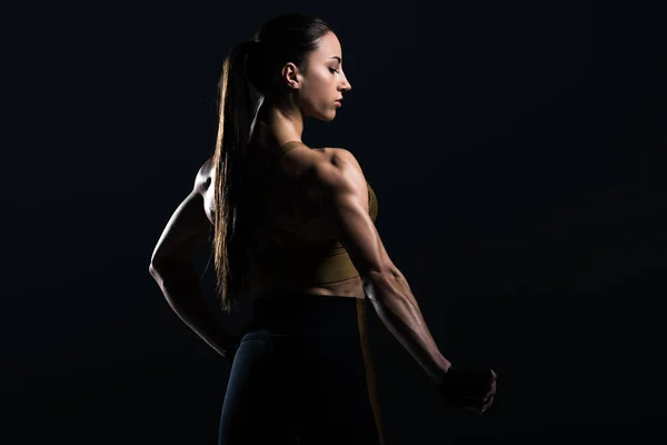 Hermosa mujer culturista posando y mostrando músculos, aislado en negro - foto de stock
