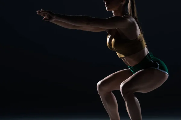 Cropped view of muscular bodybuilder doing squats, isolated on black — Stock Photo