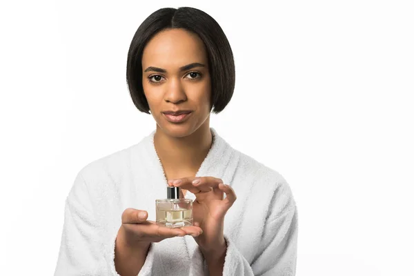 Atractiva chica afroamericana sosteniendo botella de perfume, aislado en blanco - foto de stock