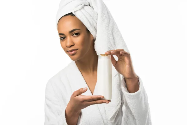 Donna afroamericana in accappatoio e asciugamano contenente lozione, isolata su bianco — Foto stock