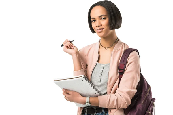Beautiful african american student with backpack writing in copybook,  isolated on white — Stock Photo