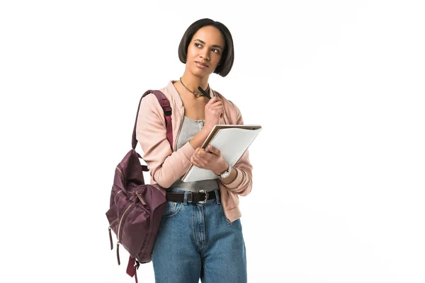 Nachdenkliche afrikanisch-amerikanische Studentin mit Rucksack-Schrift in Werbebuch, isoliert auf weiß — Stockfoto