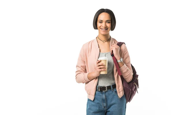 Hermosa estudiante afroamericana con mochila sosteniendo café para llevar, aislado en blanco - foto de stock