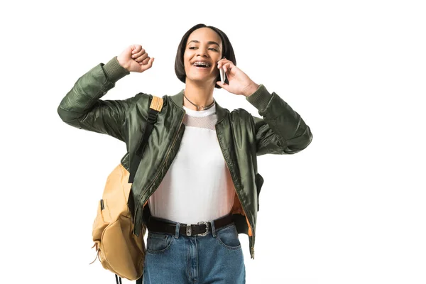 Étudiant afro-américain excité avec sac à dos parlant sur smartphone, isolé sur blanc — Photo de stock