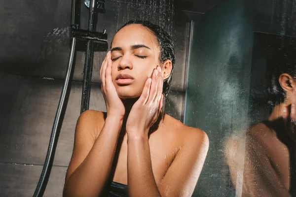 Tired african american woman washing body in shower — Stock Photo