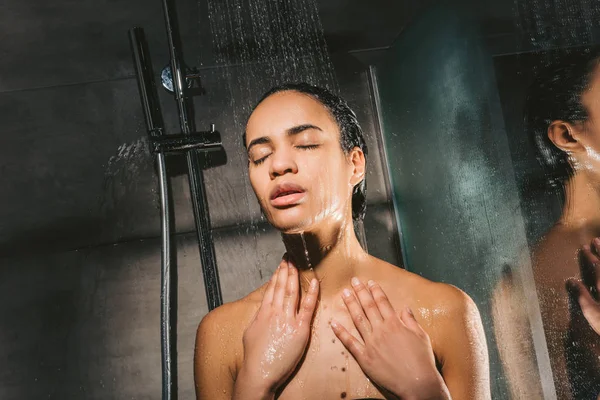 Attrayant afro-américain femme avec les yeux fermés prendre une douche — Photo de stock