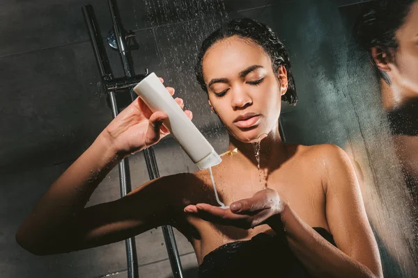 Atractivo afroamericano chica lavado cuerpo con gel de ducha - foto de stock