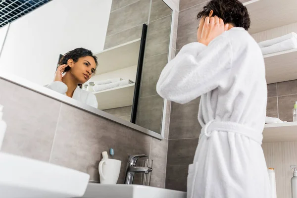 Belle afro-américaine fille regardant sa peau propre dans le miroir dans la salle de bain — Photo de stock