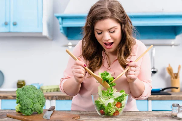 Porträt einer übergewichtigen emotionalen Frau, die zu Hause in der Küche frischen Salat für das Abendessen kocht — Stockfoto