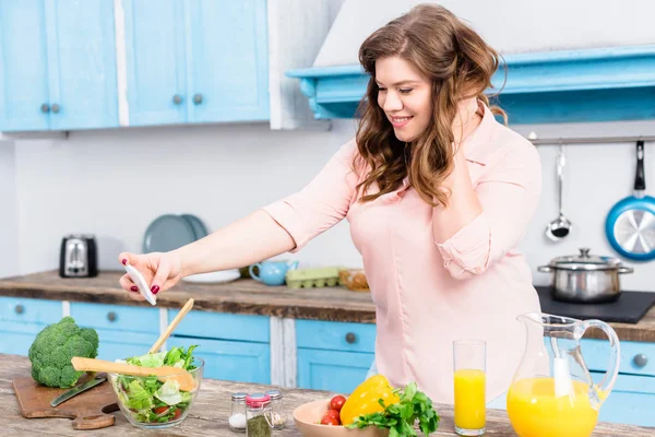 Избыточный вес улыбающаяся женщина делает селфи на смартфоне на кухне дома — стоковое фото