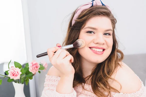 Portrait of pretty smiling young woman applying powder while doing makeup at home — Stock Photo