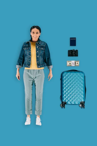 Vista superior de viajero femenino con estilo con maleta, dinero, cámara fotográfica y pasaporte aislado sobre fondo azul - foto de stock