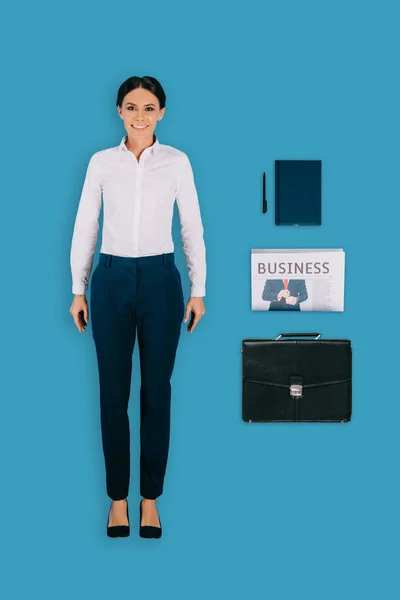 Vista superior de la mujer de negocios con maletín, libro de texto, pluma y periódico aislados sobre fondo azul - foto de stock