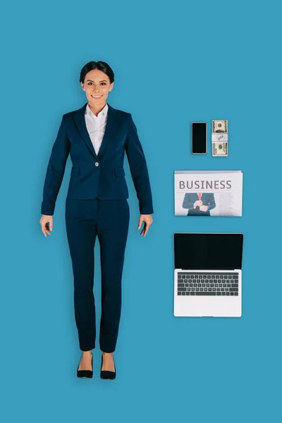Vue d'en haut de femme d'affaires avec ordinateur portable, journal, argent et smartphone isolé sur fond bleu — Photo de stock