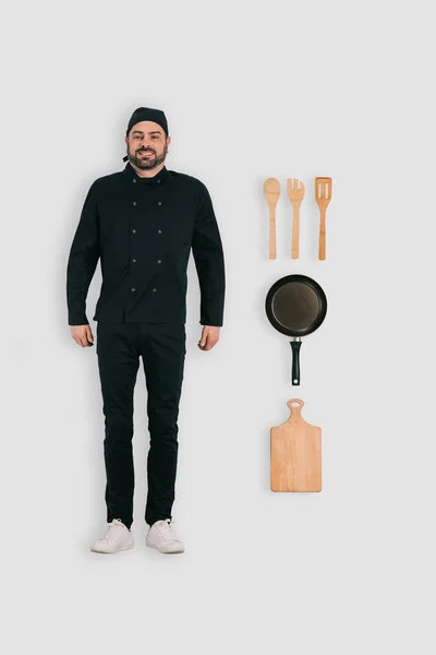 Vista superior del chef masculino con sartén, tabla de cortar y espátulas aisladas sobre fondo blanco - foto de stock