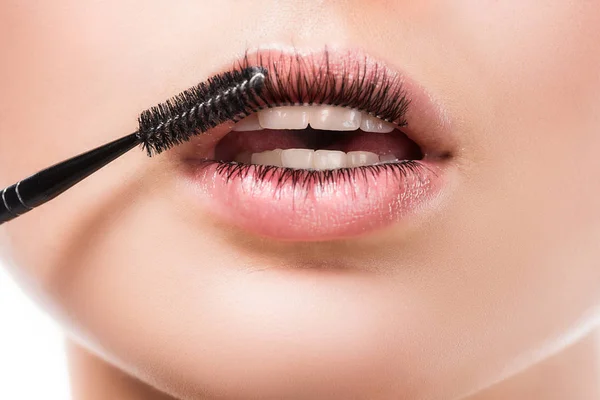 Abgeschnittenes Bild einer Frau, die Mascara auf Wimpern auf Lippen aufträgt, isoliert auf Weiß — Stockfoto
