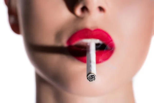 Imagen recortada de la mujer sosteniendo el cigarrillo con los labios rojos, cigarrillo en primer plano - foto de stock