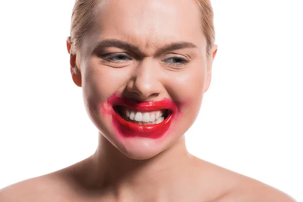 Mujer emocional con lápiz labial rojo manchado en la cara que muestra los dientes aislados en blanco - foto de stock