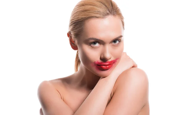 Joyeuse belle femme avec rouge à lèvres rouge barbouillé sur le visage en regardant la caméra isolée sur blanc — Photo de stock