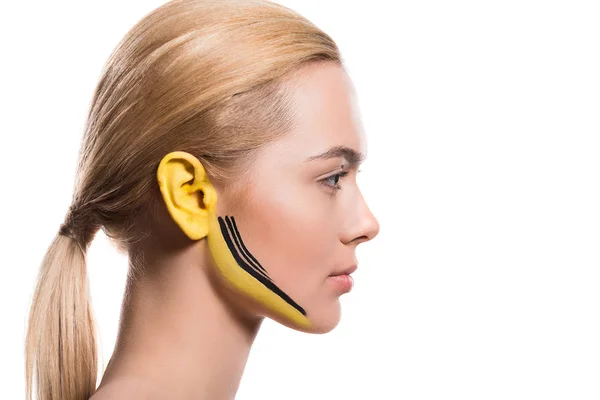 Vista lateral da mulher bonita com tintas amarelas e pretas na orelha e rosto isolado no branco — Fotografia de Stock