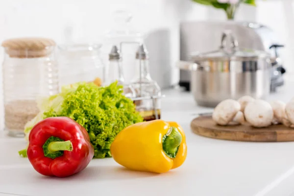 Red and yellow bell peppers and green lettuce in kitchen — Stock Photo