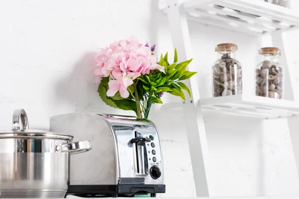 Toaster, saucepan and pink flowers in kitchen — Stock Photo