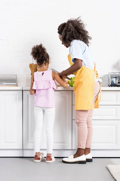 Afro-américaine mère et fille couper des légumes sur la cuisine ensemble — Photo de stock